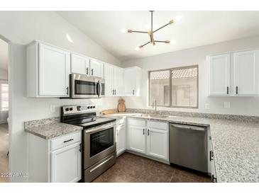 Bright kitchen showcasing white cabinetry, stainless steel appliances, granite countertops, and modern lighting fixtures at 13267 W Port Au Prince Ln, Surprise, AZ 85379