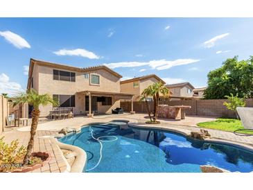 Inviting backyard oasis with sparkling pool, lush landscaping, and outdoor entertaining area at 14334 W Avalon Dr, Goodyear, AZ 85395