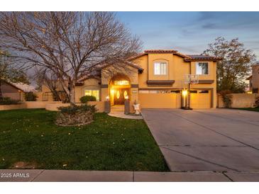 Inviting two-story home with a well-manicured lawn, a driveway, and a large tree in the front yard at 15011 N 45Th Pl, Phoenix, AZ 85032