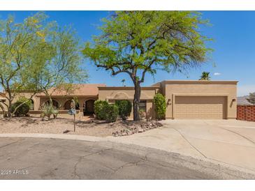 Tan home with a desert landscape, mature tree, and a spacious driveway leading to a two-car garage at 15843 E Mustang Dr, Fountain Hills, AZ 85268