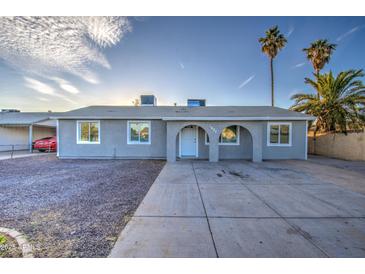 Charming single-story home featuring a well-maintained yard, complemented by mature palm trees and a concrete driveway at 1630 N 58Th Ave, Phoenix, AZ 85035