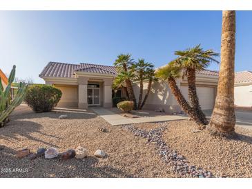 Charming single-story home with desert landscaping and mature palm trees in the front yard at 22120 N Old Mine Rd, Sun City West, AZ 85375