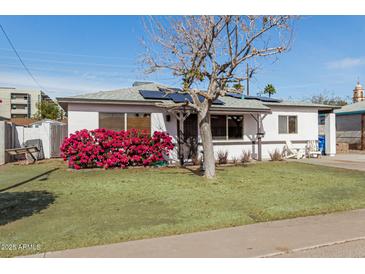 Charming single-story home with a landscaped yard, solar panels and cozy seating area at 2302 E Sells Dr, Phoenix, AZ 85016