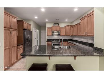 Well-lit kitchen features stainless steel appliances, granite counters, and a breakfast bar with seating at 28735 N 21St Ave, Phoenix, AZ 85085