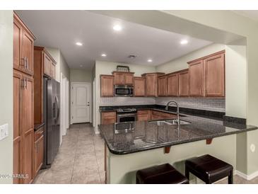 Well-lit kitchen features stainless steel appliances, granite counters, and a breakfast bar with seating at 28735 N 21St Ave, Phoenix, AZ 85085