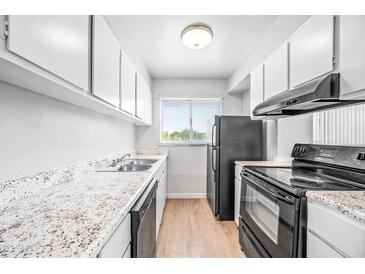 Galley kitchen featuring white cabinets, stainless steel appliances, and stone-look countertops at 4867 W Palo Verde Dr, Glendale, AZ 85301