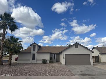 Charming single-story home with a two-car garage, desert landscaping, and palm trees under a blue sky at 5552 W Willow Ave, Glendale, AZ 85304