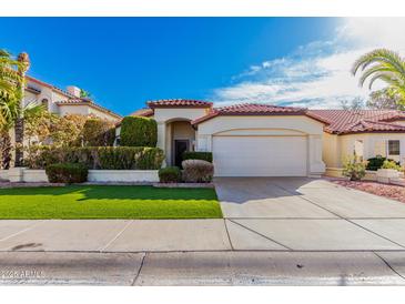 Charming single-story home featuring a red tile roof, lush landscaping, and an attached two-car garage at 9633 S 51St St, Phoenix, AZ 85044