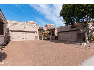 Charming home featuring a two-car garage, and a brick-paved driveway, all under a bright blue sky at 6202 E Mckellips Rd # 210, Mesa, AZ 85215