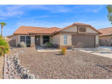 Charming home with a terracotta tile roof, desert landscaping, and an attached garage at 13947 N 75Th Dr, Peoria, AZ 85381