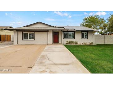 Charming single-story home with a well-manicured lawn, solar panels, and a long concrete driveway at 15031 N 37Th Ave, Phoenix, AZ 85053