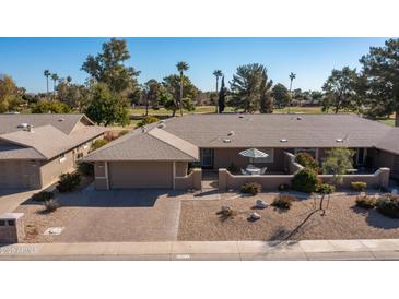 Charming home with well-maintained landscaping, brick driveway, and gated courtyard with table and seating at 19217 N Concho Cir, Sun City, AZ 85373