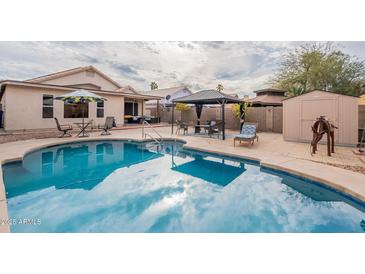 Inviting backyard pool with covered seating area, shed, and meticulously maintained surroundings at 316 W Kelton Ln, Phoenix, AZ 85023