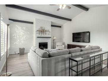 Bright living room features vaulted ceilings, white brick fireplace, and large sectional sofa at 4800 N 68Th St # 385, Scottsdale, AZ 85251