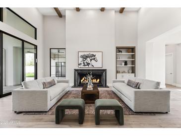 Bright living room featuring a black marble fireplace, wood beams, and modern gray sofas at 6500 E Cactus Wren Rd, Paradise Valley, AZ 85253