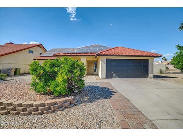 Charming single-story home with a tile roof, solar panels, and desert landscaping at 7102 W Julie Dr, Glendale, AZ 85308