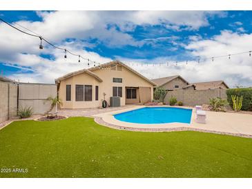 Inviting backyard with a sparkling pool, lush turf, string lights, and privacy at 20966 N 84Th Ln, Peoria, AZ 85382