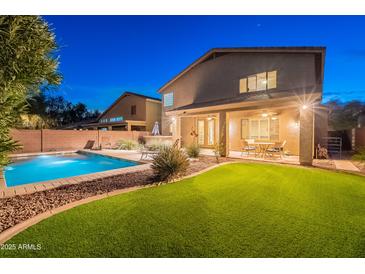 Expansive backyard featuring pool, covered patio, artificial grass, and desert landscaping at 26711 N 21St Dr, Phoenix, AZ 85085
