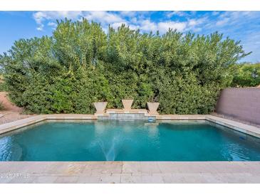 Inviting pool area with travertine tile and lush landscaping, perfect for relaxation and outdoor enjoyment at 26711 N 21St Dr, Phoenix, AZ 85085