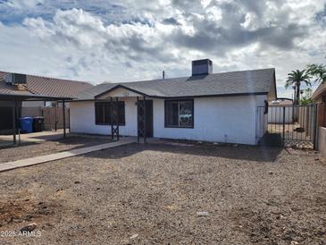 Well-maintained single-story home with a carport and easy desert landscaping, fenced for privacy at 3123 W Holly St, Phoenix, AZ 85009