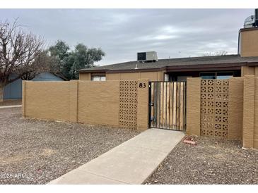 Tan block wall with a gated entry and walkway to this residential home at 3646 N 67Th Ave # 83, Phoenix, AZ 85033