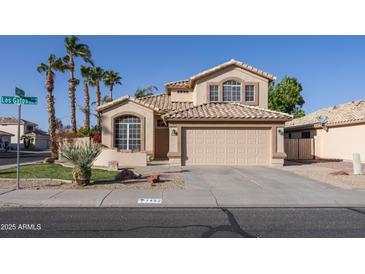 Charming two-story home featuring a neutral exterior, a well-manicured lawn, desert landscaping, and a two-car garage at 7452 W Los Gatos Dr, Glendale, AZ 85310