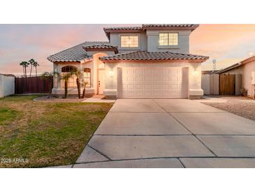 Two-story home featuring a tile roof, arched entryway, well-manicured lawn, and a two-car garage at 7953 W Topeka Dr, Glendale, AZ 85308
