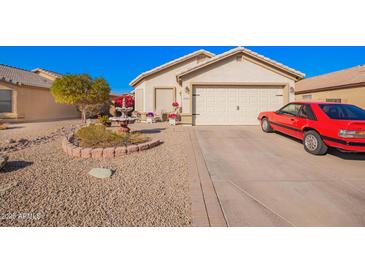 Charming single-story home featuring a well-manicured yard, desert landscaping and a classic red car in the driveway at 10664 E Emerald Ave, Mesa, AZ 85208