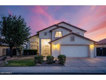 Charming two-story home featuring a two car garage, desert landscaping, and a tile roof at dusk at 16161 W Monte Cristo Ave, Surprise, AZ 85374