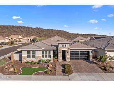 Beautiful single-story home featuring a stone facade, desert landscaping, and a brick driveway at 30331 N 115Th Ln, Peoria, AZ 85383