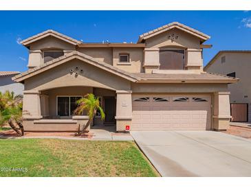 Two-story home featuring a front yard and covered porch that leads to a two car garage and desert landscaping at 3907 N 143Rd Ln, Goodyear, AZ 85395