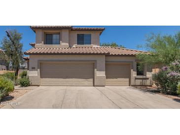 Three car garage in a two-story tan home with a tile roof at 6350 W Hess St, Phoenix, AZ 85043