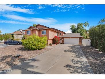 Two-story home with a long driveway and an attached garage against a bright blue sky at 713 N Banning Cir, Mesa, AZ 85205