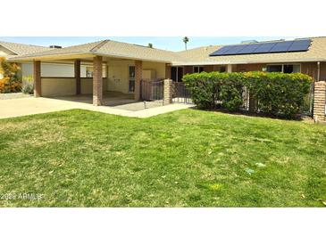 Single-story home showcasing a well-manicured lawn, carport, and gated patio area at 10816 W Venturi Dr, Sun City, AZ 85351