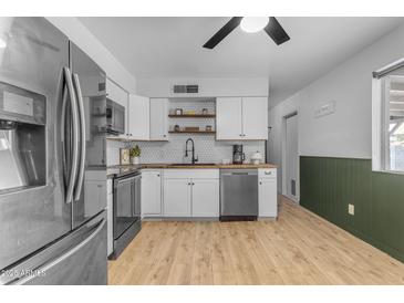 Bright kitchen with stainless steel appliances, white cabinets, and butcher block countertops at 248 S 95Th Pl, Chandler, AZ 85224