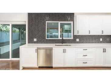 Bright kitchen features white cabinets, stainless steel appliances, and stylish herringbone backsplash at 4735 N 24Th St, Phoenix, AZ 85016