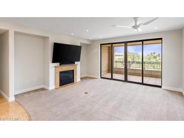 Open living room with fireplace, flat screen tv, and sliding doors to balcony at 7175 E Camelback Rd # 307, Scottsdale, AZ 85251