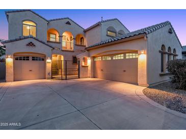 Elegant two-story home featuring a three-car garage, arched entryway, gated courtyard, and tile roof in a warm neutral palette at 15635 W Montecito Ave, Goodyear, AZ 85395