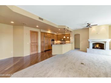 Open-concept living area with a fireplace and an adjacent kitchen featuring wood cabinetry and granite countertops at 15802 N 71St St # 604, Scottsdale, AZ 85254