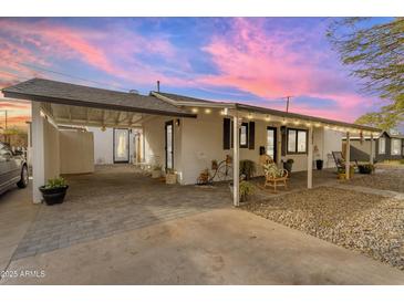 Charming single-story home boasts a covered parking area and a welcoming front porch with seating at 303 W Hazelwood St, Phoenix, AZ 85013