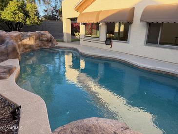 Inviting in-ground pool with stone waterfall feature and desert landscaping at 4336 E Encanto St, Mesa, AZ 85205