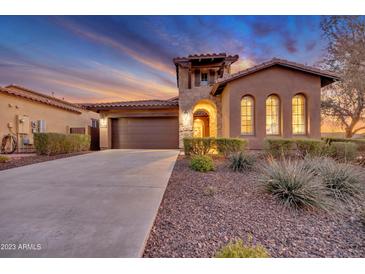 Beautiful Tuscan-style home featuring a stone tower, arched entry, and a well-manicured front yard with desert landscaping at 13719 W Creosote Dr, Peoria, AZ 85383