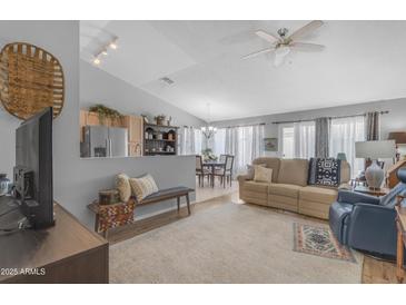 Open-concept living room features neutral tones, ceiling fan, and seamless flow to dining area at 1706 E Lindrick Dr, Chandler, AZ 85249