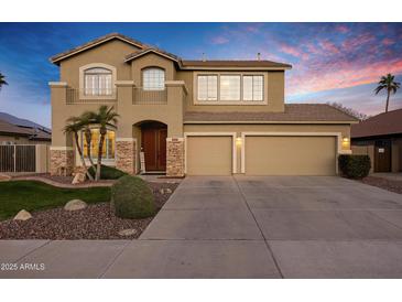 Two-story tan home with a three-car garage, stone accents and beautiful desert landscaping at 3017 S Mesita --, Mesa, AZ 85212