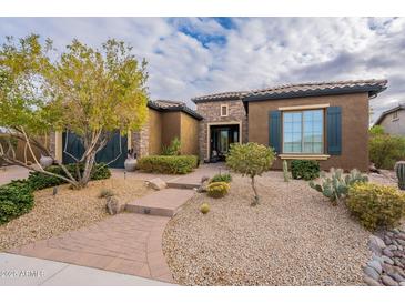 Charming single-story home featuring desert landscaping, a stone accent wall, and a brick walkway at 5921 E Ocupado Dr, Cave Creek, AZ 85331