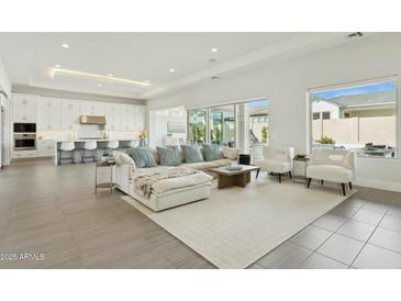 Spacious living room features a large sectional sofa, modern decor, and an open floor plan leading to the kitchen at 9370 E Wethersfield Rd, Scottsdale, AZ 85260