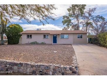 Charming single-story home showcasing a low-maintenance rock yard and inviting blue front door at 99 W Circle Dr, Florence, AZ 85132