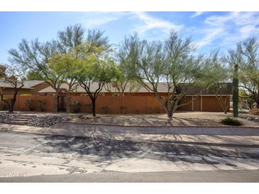 Street view of home with rock landscaping, desert trees, and orange wall with gate feature at 1301 E Belmont Ave, Phoenix, AZ 85020