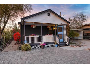 Charming home featuring a quaint front porch adorned with colorful flowers and an inviting paver walkway at 1546 W Polk St, Phoenix, AZ 85007