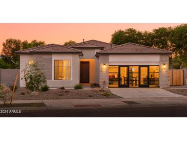 Beautiful single-story home with a well-manicured yard, covered entry, and attached garage at sunset at 15667 W Mercer Ln, Surprise, AZ 85379